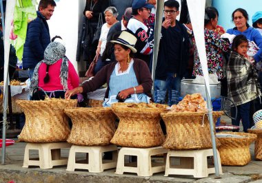 Cuenca, Ekvador - 23 Eylül 2018 Cuenca sokak pazarı. Büyük sepetleri olan yerli kadınlar mısır koçanı yaprağının içinde pişirilen Tamale ve Humitas gibi abur cuburlar satıyorlar.