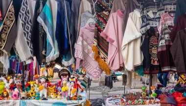 Otavalo, Ekvador - 28 Haziran 2025: Otavalo, Ekvador 'da haftalık Plaza de los Ponchos pazarında çeşitli renklerde geleneksel Andean pançoları ve çeşitli hediyelik eşyalar satılmaktadır.