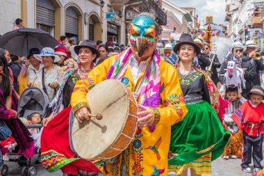 Cuenca, Ekvador 24 Aralık 2024: Davullu bir folklor karakteri, bir grup dansçı ve bir grup vatandaş Cuenca 'daki yıllık Pase del Nio Viajero Noel geçit töreninde eğleniyorlar.