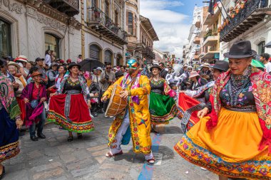 Cuenca, Ekvador 24 Aralık 2024: Davullu bir folklor karakteri, bir grup dansçı ve bir grup vatandaş Cuenca 'daki yıllık Pase del Nio Viajero Noel geçit töreninde eğleniyorlar.