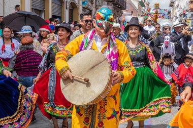 Cuenca, Ekvador 24 Aralık 2024: Davullu bir folklor karakteri, bir grup dansçı ve bir grup vatandaş Cuenca 'daki yıllık Pase del Nio Viajero Noel geçit töreninde eğleniyorlar.