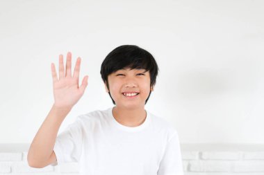 Beyaz arka planda selamlaşmak için el sallayan Asyalı çocuk portresi
