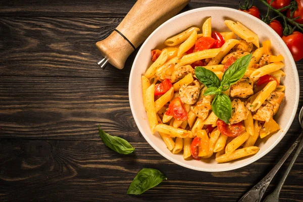 Pasta con pollo y verduras a la mesa de madera. — Foto de Stock