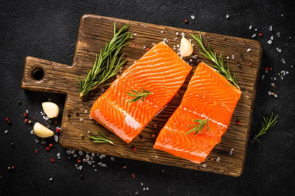 Pescado salmón con ingredientes a la mesa negra. — Foto de Stock