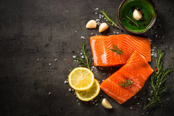 Pesce salmone con ingredienti a tavola nera. — Foto Stock