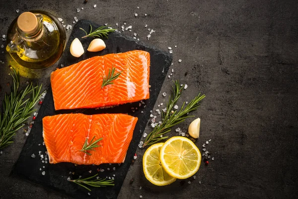 Salmon fish with ingredients at black table. — Stock Photo, Image