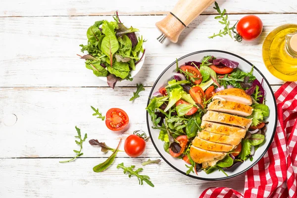 Green salad with baked chicken breast at white table. — Stock Photo, Image