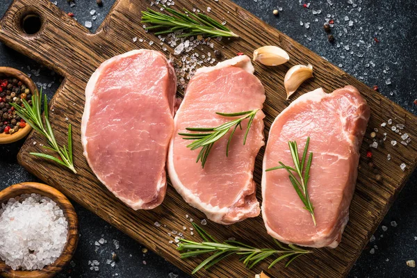 Fresh pork steaks on cutting board with ingredients for cooking. — Stock Photo, Image