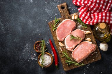 Tahtada taze domuz bifteği ve yemek malzemeleri var..