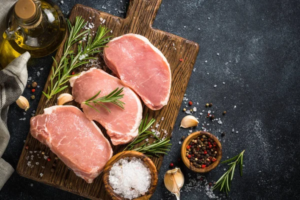 Fresh pork steaks on cutting board with ingredients for cooking. — Stock Photo, Image