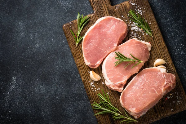 Fresh pork steaks on cutting board with ingredients for cooking. — Stock Photo, Image