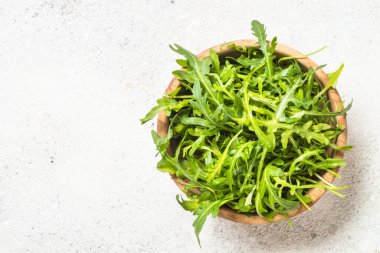 Arugula beyaz masada taze yeşil yapraklar.