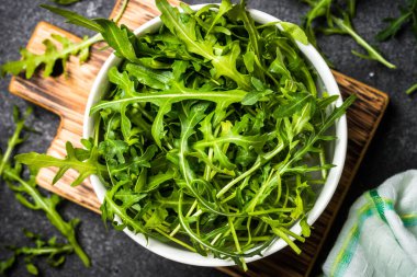 Arugula taze yeşil yapraklar siyah taş masada.