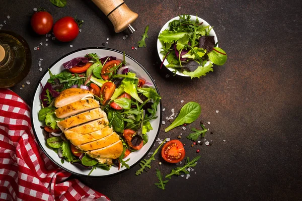 Green salad with baked chicken breast at kitchen table. — Stock Photo, Image