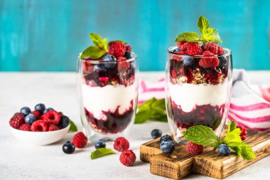 Parfait with granola, jam and fresh berries in the glass jar.