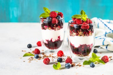 Parfait with granola, jam and fresh berries in the glass jar.