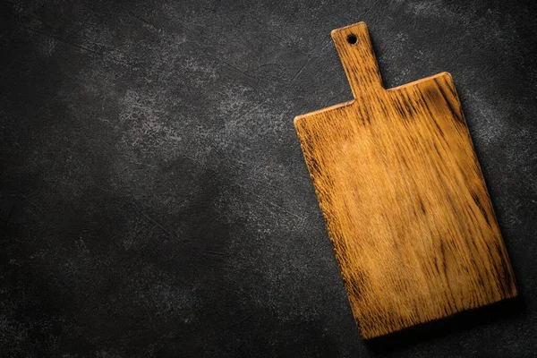 Wooden cutting board at black stone table. — Stock Photo, Image