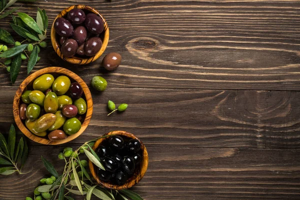 Aceitunas negras y verdes sobre mesa de madera. — Foto de Stock