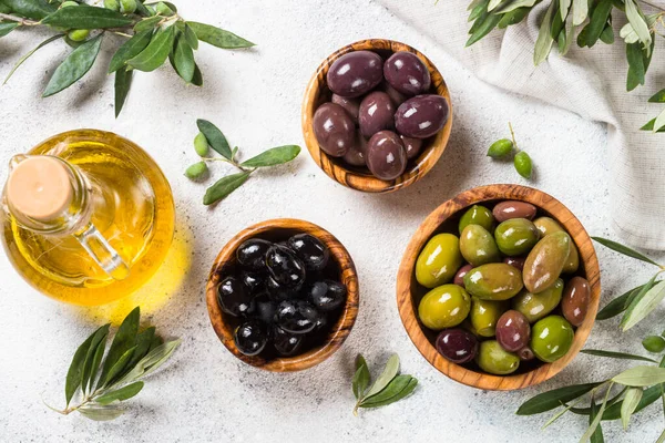Natural greek Olives in wooden bowls and olive oil bottle on white background. — Stock Photo, Image