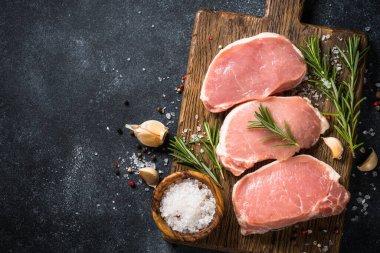 Tahtada taze domuz bifteği ve yemek malzemeleri var..