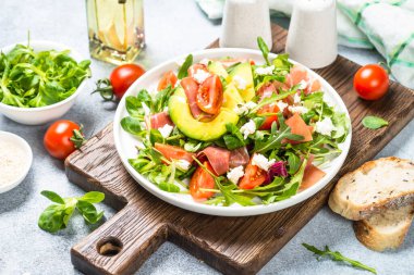 Yeşil yapraklı taze salata, jamon ve domates..