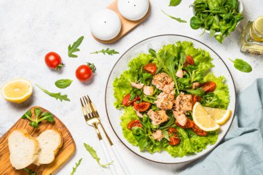 Beyaz masada fırında balık ve yeşil salata..