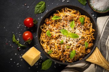 Siyah masadaki tavada makarna bolonez.