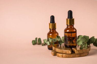 Pastel arka planda taze yapraklı serum şişesi..