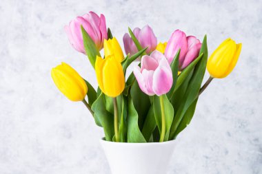 Beyaz seramik vazoda açık arkaplanda laleler çiçek buketi.