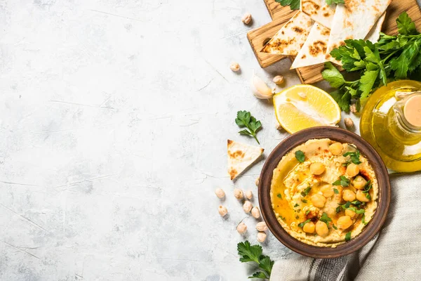 Hummus with olive oil and paprika at light kitchen table.