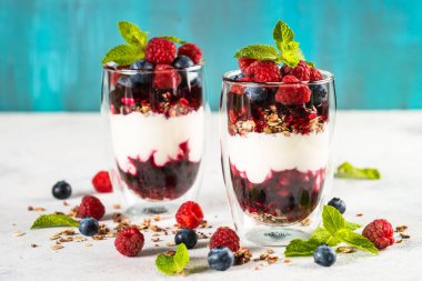 Parfait with granola, jam and fresh berries in the glass jar.