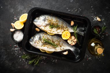 Çiğ balık dorado, siyah taş masadaki kabartma çarşafında..