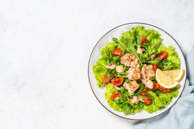 Beyaz masada fırında balık ve yeşil salata..