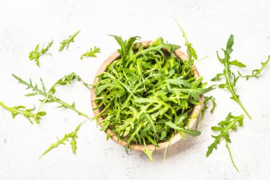 Arugula beyaz masada taze yeşil yapraklar.