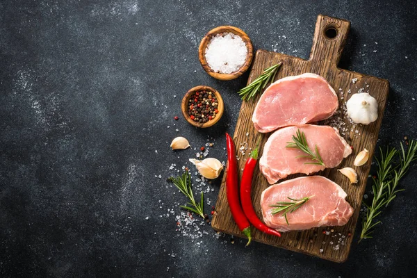 Vers varkensvlees steaks op snijplank met ingrediënten voor het koken. — Stockfoto