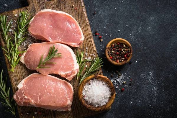 Filetes de cerdo frescos en la tabla de cortar con ingredientes para cocinar. —  Fotos de Stock