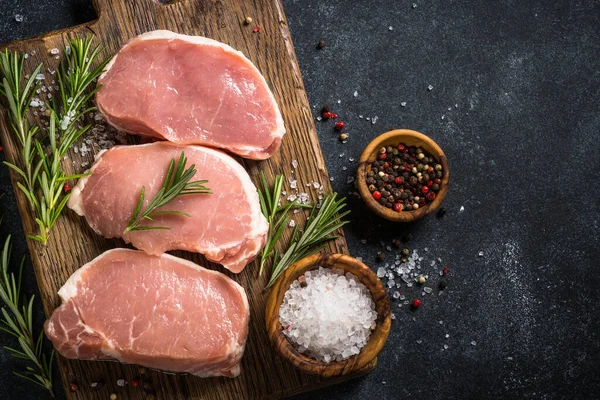 Fresh pork steaks on cutting board with ingredients for cooking. — Stock Photo, Image