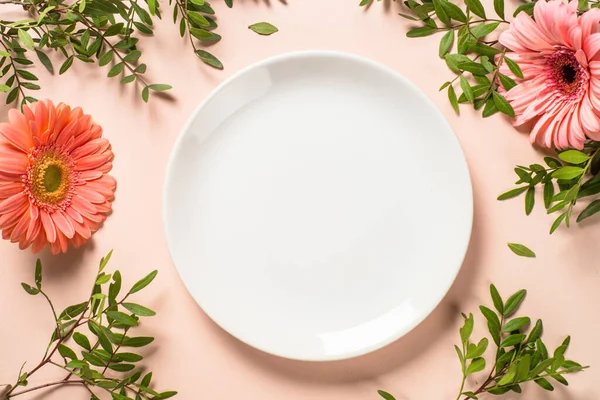 Cadre de table avec assiette blanche, couverts et fleurs. — Photo