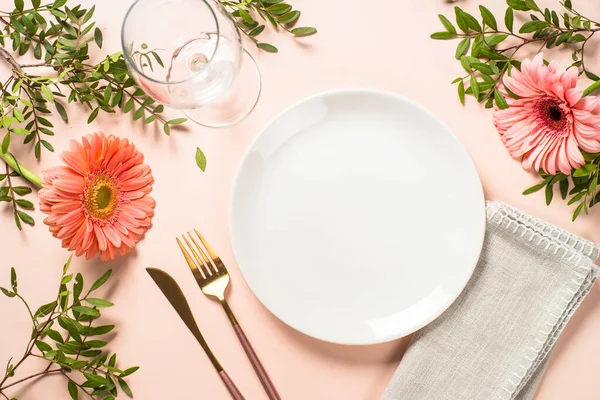 Cadre de table avec assiette blanche, couverts et fleurs. — Photo