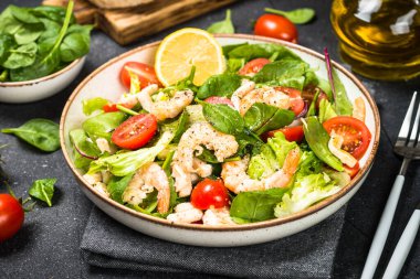 Taş masada yeşil yapraklı karides salatası..
