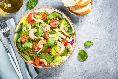 Taş masada yeşil yapraklı karides salatası..