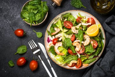 Taş masada yeşil yapraklı karides salatası..