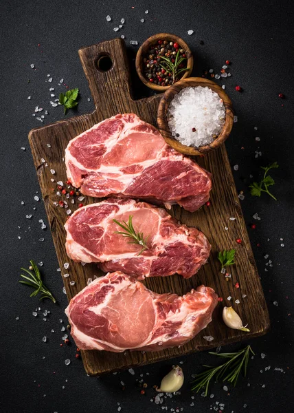 Carne de cerdo en tablero de madera sobre mesa negra. —  Fotos de Stock