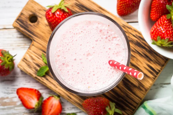 Erdbeer-Smoothie oder Milchshake am weißen Tisch. — Stockfoto