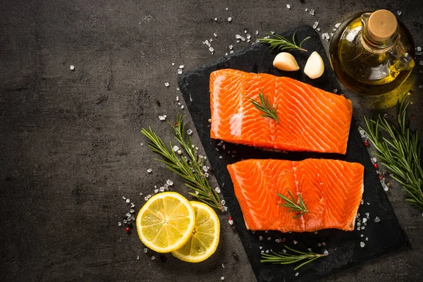 Pesce salmone con ingredienti a tavola nera. — Foto Stock