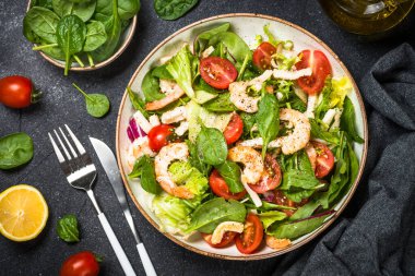 Taş masada yeşil yapraklı karides salatası..