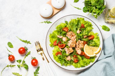 Beyaz masada fırında balık ve yeşil salata..