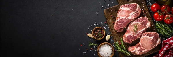 Carne de cerdo en tablero de madera sobre mesa negra. — Foto de Stock