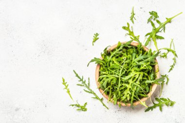 Arugula beyaz masada taze yeşil yapraklar.