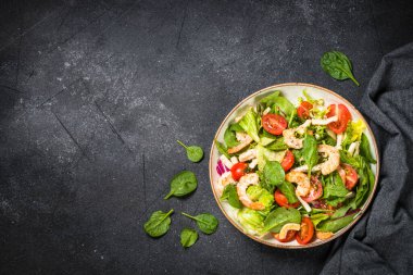 Taş masada yeşil yapraklı karides salatası..
